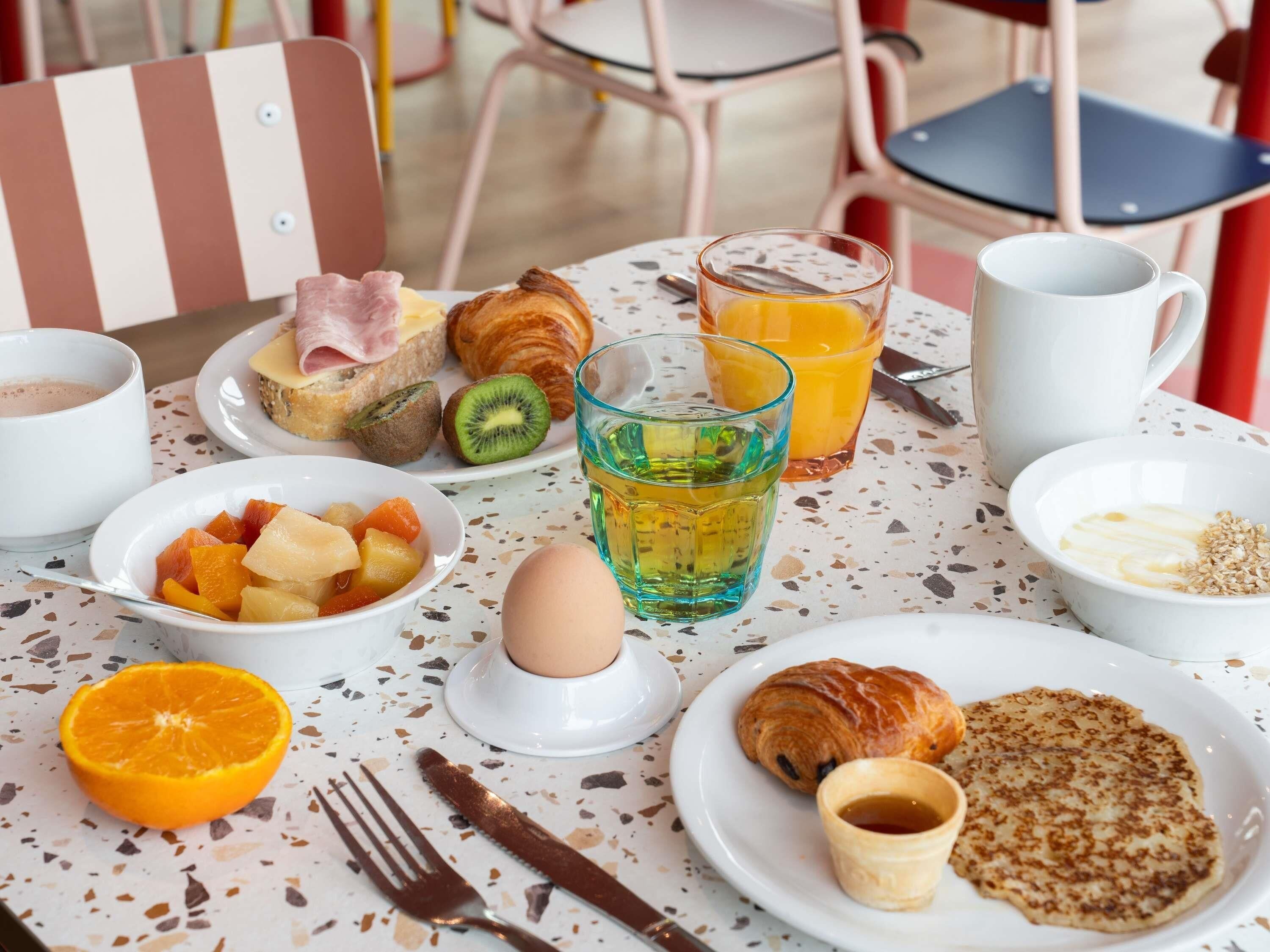 A breakfast setting with croissants, fruit, juice, and a cup of coffee on a table.