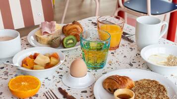 A breakfast setting with croissants, fruit, juice, and a cup of coffee on a table.