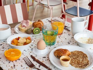 A breakfast setting with croissants, fruit, juice, and a cup of coffee on a table. - ibis budget Tours Nord (Tours)