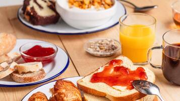 A breakfast setting with bread, jam, a bowl of cereal, and a glass of orange juice.
