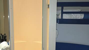 A hotel room with a shower, a bunk bed, and a mirror.