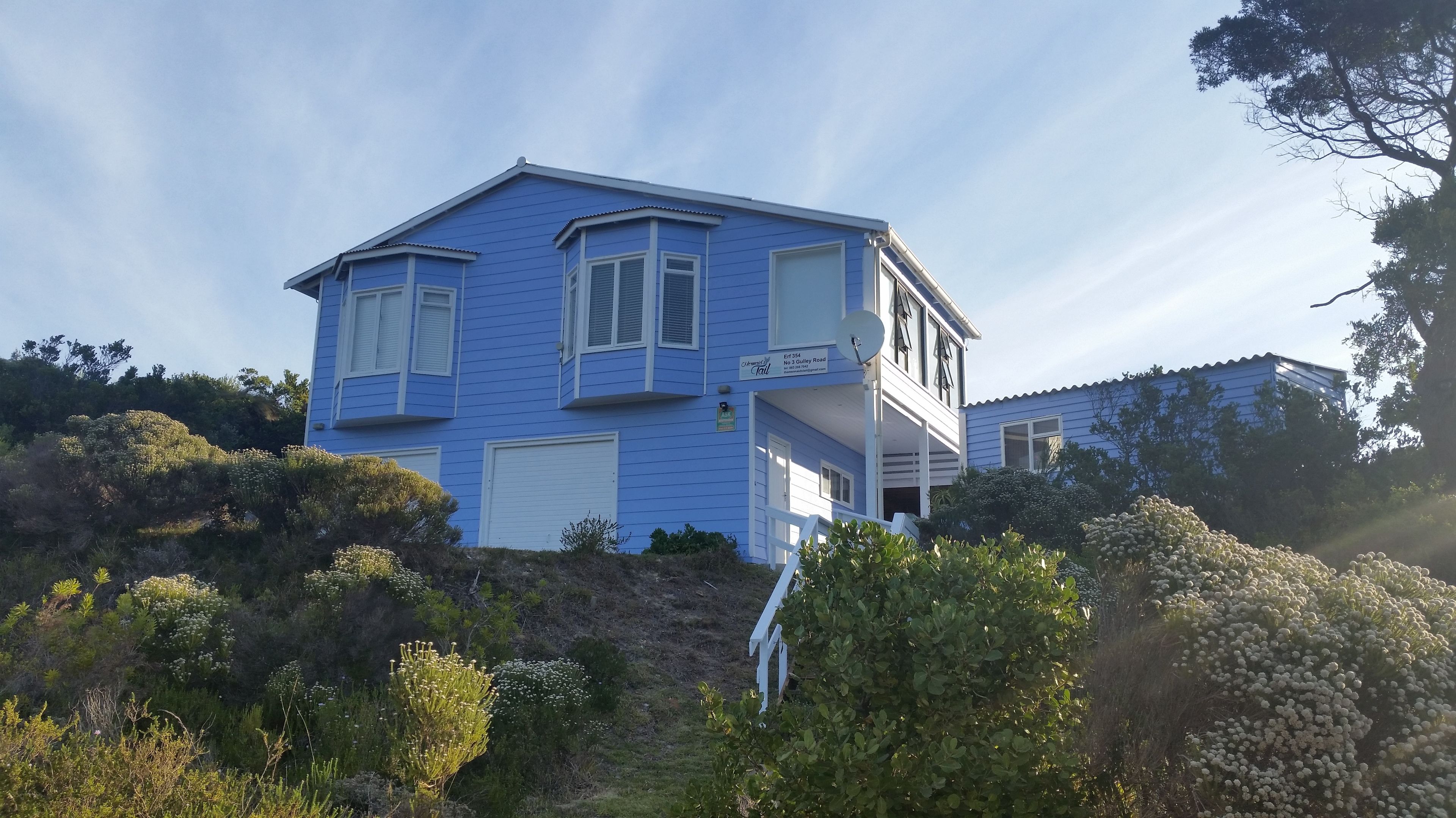 A two-story house with a blue exterior, a covered porch, and a garage.