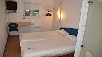 A bedroom with a bed, a desk, a chair, a TV, and a window.