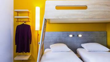 Una habitación con una cama litera, un estante pequeño con una bata y una lámpara fijada a la pared.