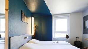 Een hotelkamer met twee bedden, een groot raam, een televisie en een koffer.