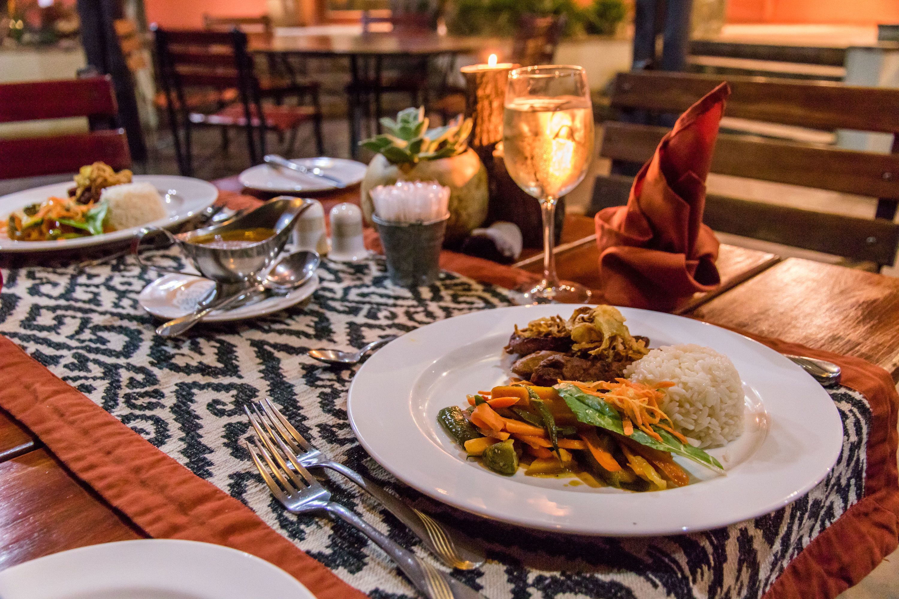 Una mesa de comedor dispuesta con platos de comida, cubiertos y una vela.