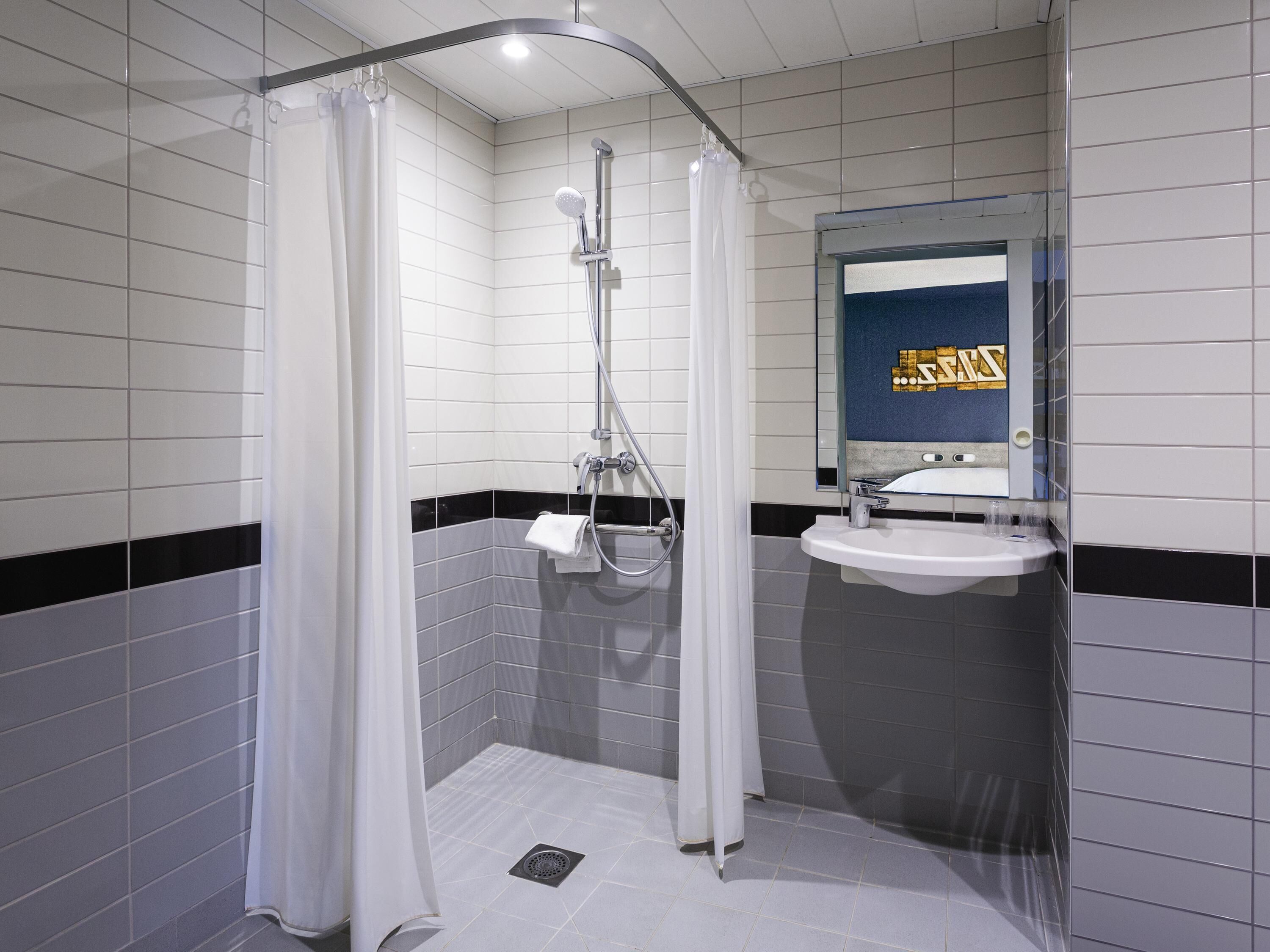 A modern bathroom with a shower, a sink, and a mirror.