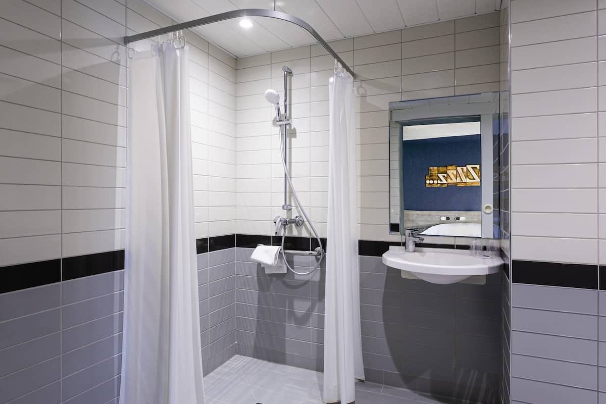 A modern bathroom with a shower, a sink, and a mirror.