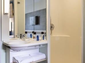 Ein Badezimmer mit zwei Waschbecken, einem Spiegel, einem Handtuchhalter und einer Dusche.