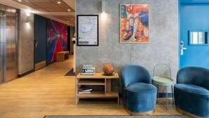 A modern lobby with a blue door, a map poster, and seating area. - ibis budget Meudon Paris Ouest (Meudon)