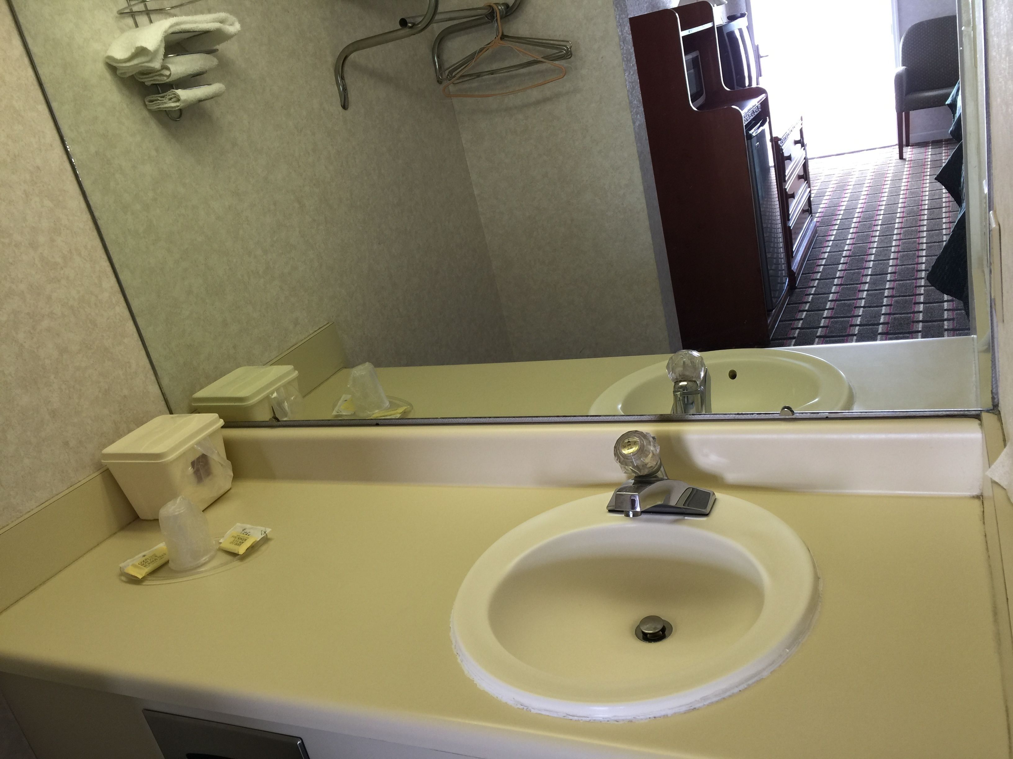 A bathroom with a sink, mirror, and towel rack.