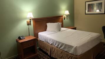 Quarto de hotel com uma cama grande, duas mesas de cabeceira, um telefone e duas luminárias na parede.