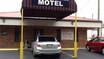 A Heritage Inn Motel with a prominent sign, a brick building, and a parking lot with two cars.