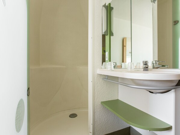 A bathroom with a white sink, green shelf, and a mirror.