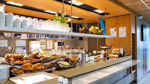 A breakfast buffet with pastries, bread, and beverages.