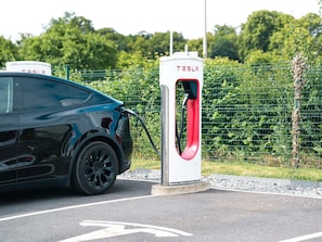 A Tesla electric car charging at a station.