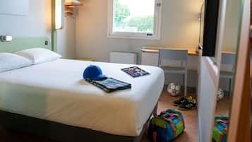 Een hotelkamer met een bed, bureau, stoel, raam en televisie.