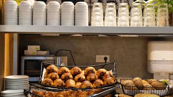 Ein Buffet mit Croissants, Brot und Gläsern.