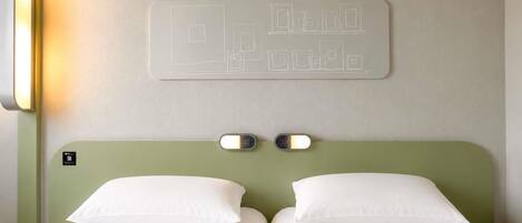 Ein Hotelzimmer mit einem Bett, zwei Nachttischlampen und einer Wandleuchte.