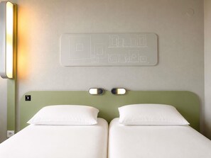 A hotel room with a bed, two bedside lamps, and a wall-mounted light fixture. - ibis budget Caen Porte de Bretagne (Bretteville-sur-Odon)