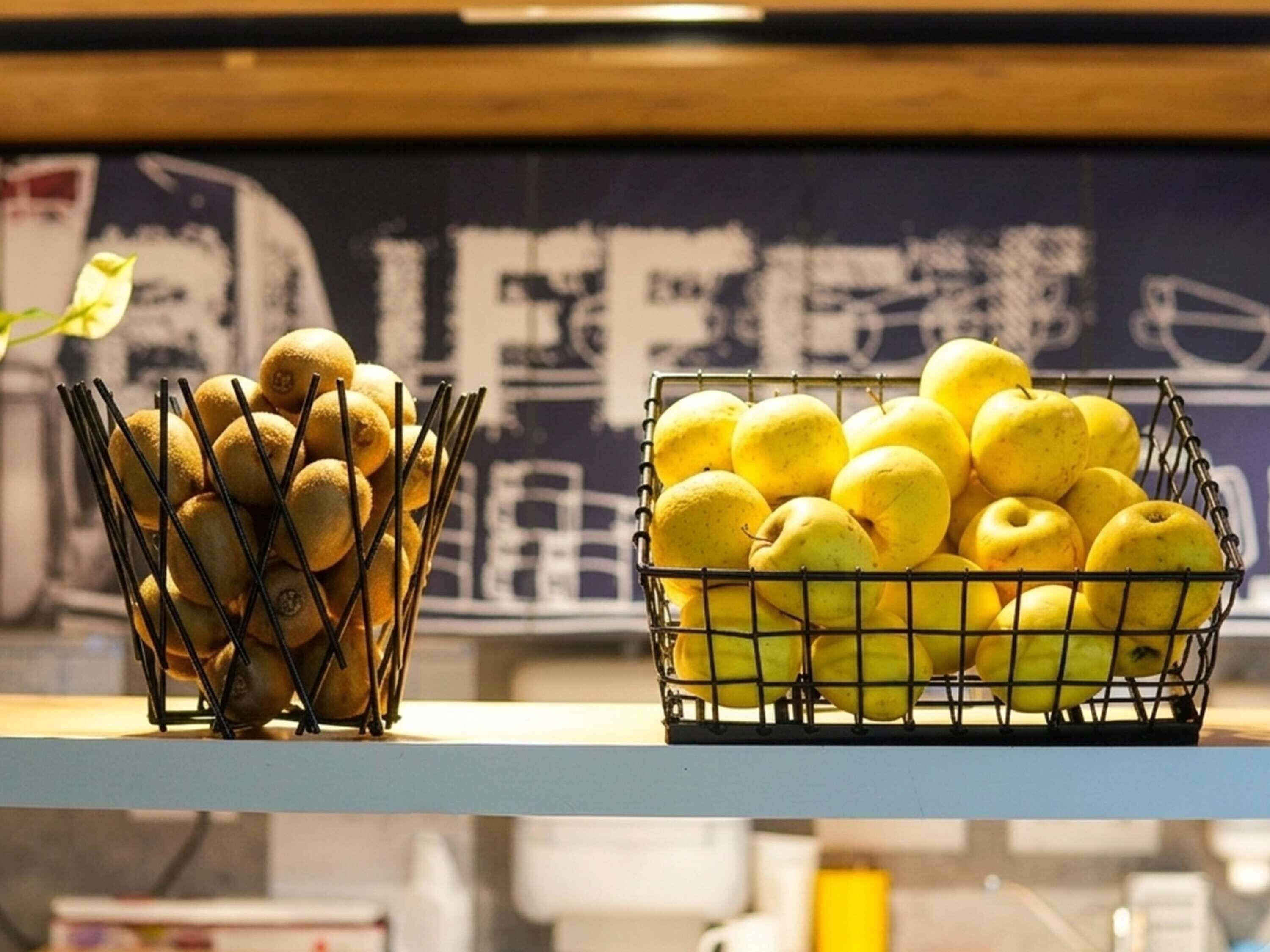 Una encimera de cocina con dos cestas de alambre que contienen fruta.