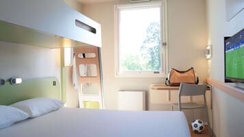 A hotel room with a bed, a desk, a chair, a television, and a window.