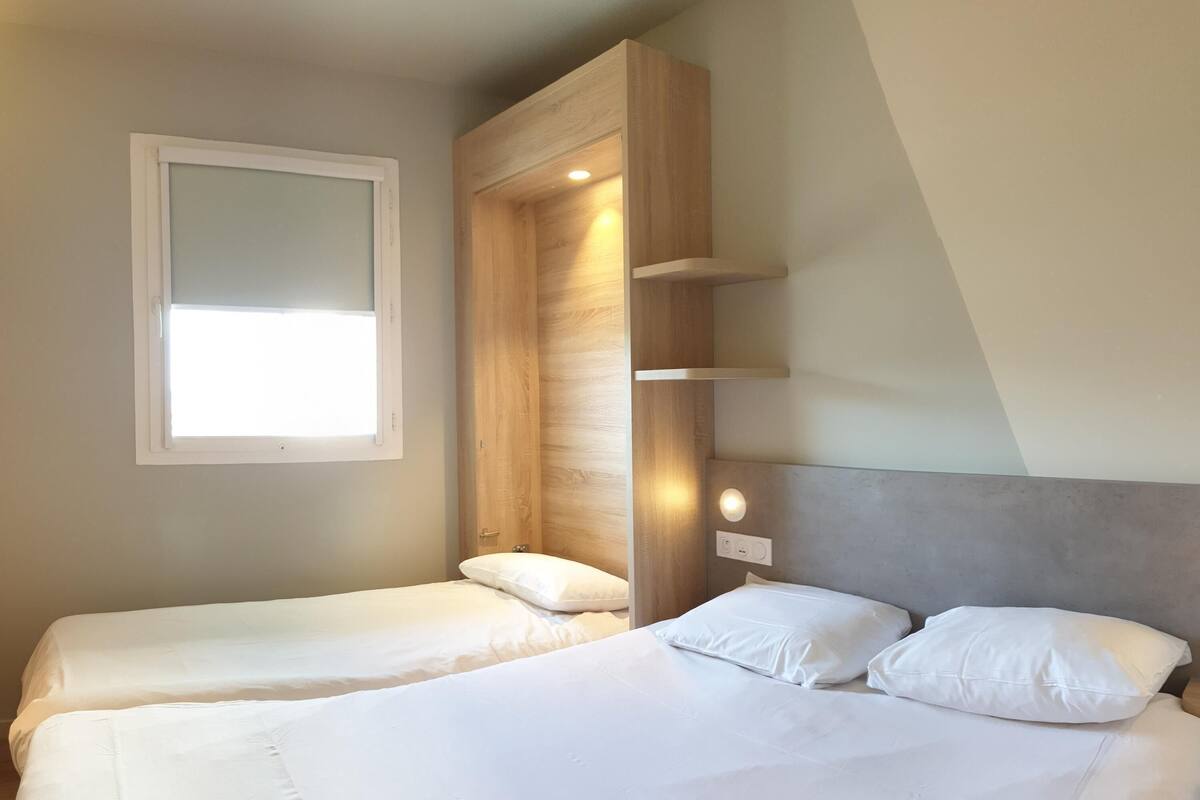 A bedroom with two beds, a window, and built-in shelves.