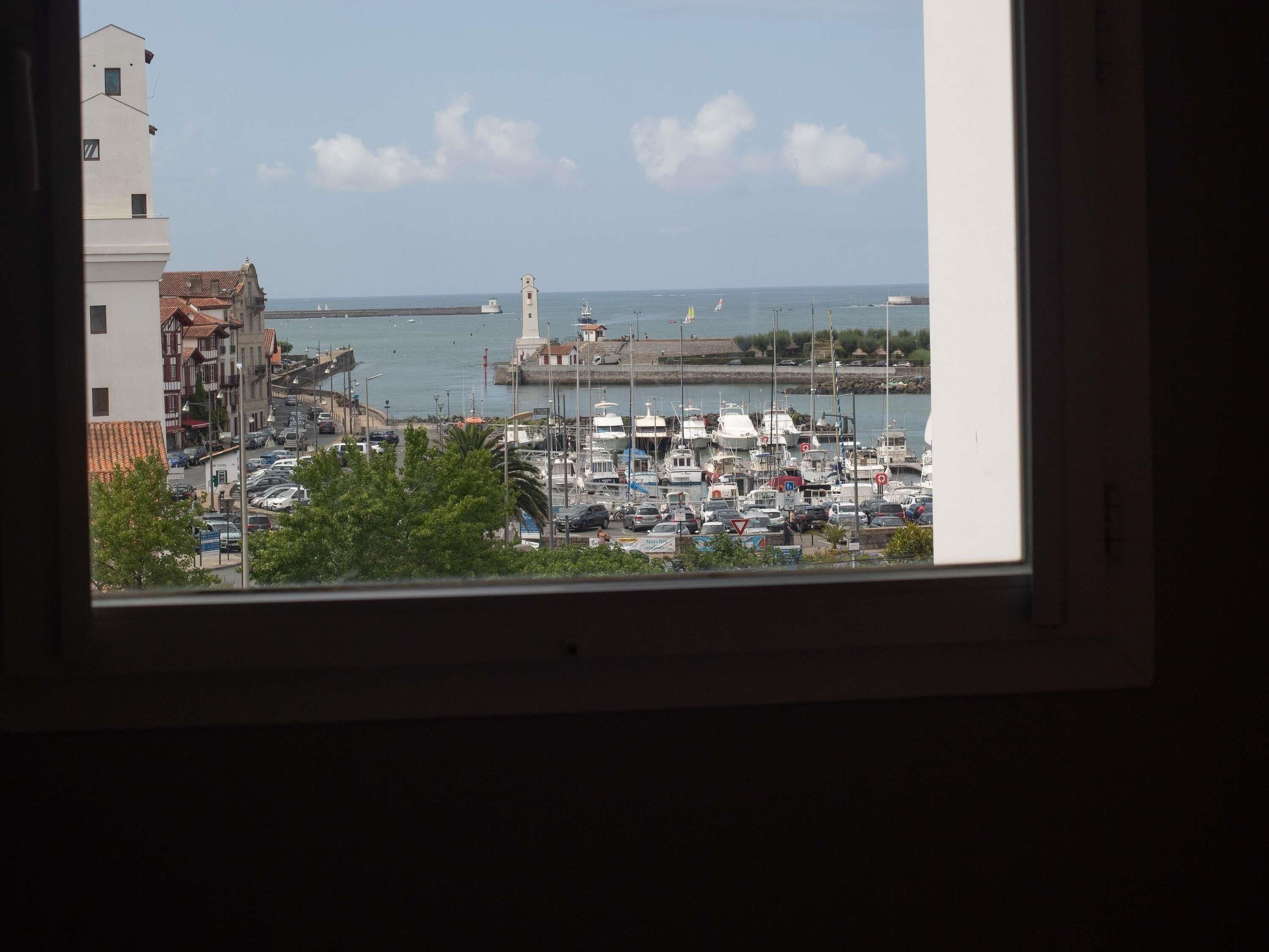 A marina with boats, a lighthouse, and buildings in the background.