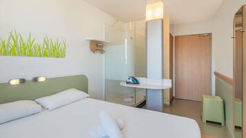 Een hotelkamer met een bed, een douche en een klein zithoekje.