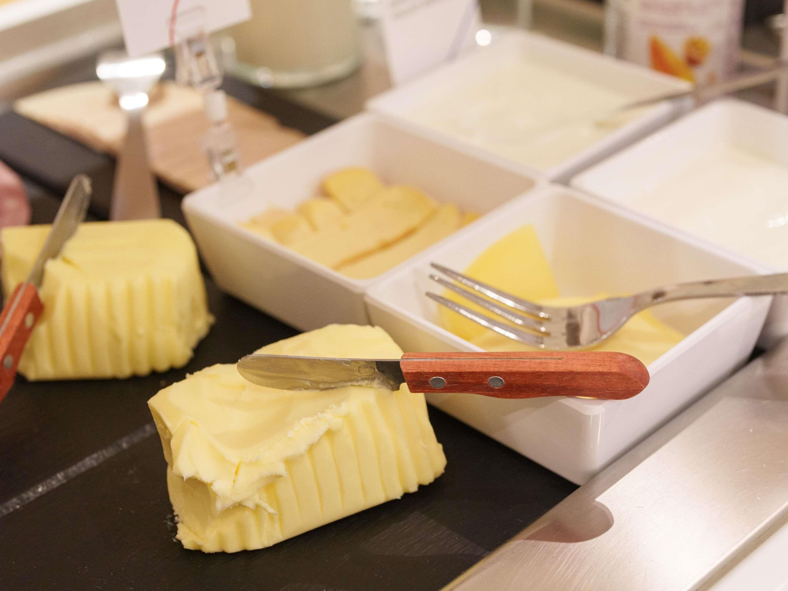 A buffet with multiple containers of butter and a knife on a tray.
