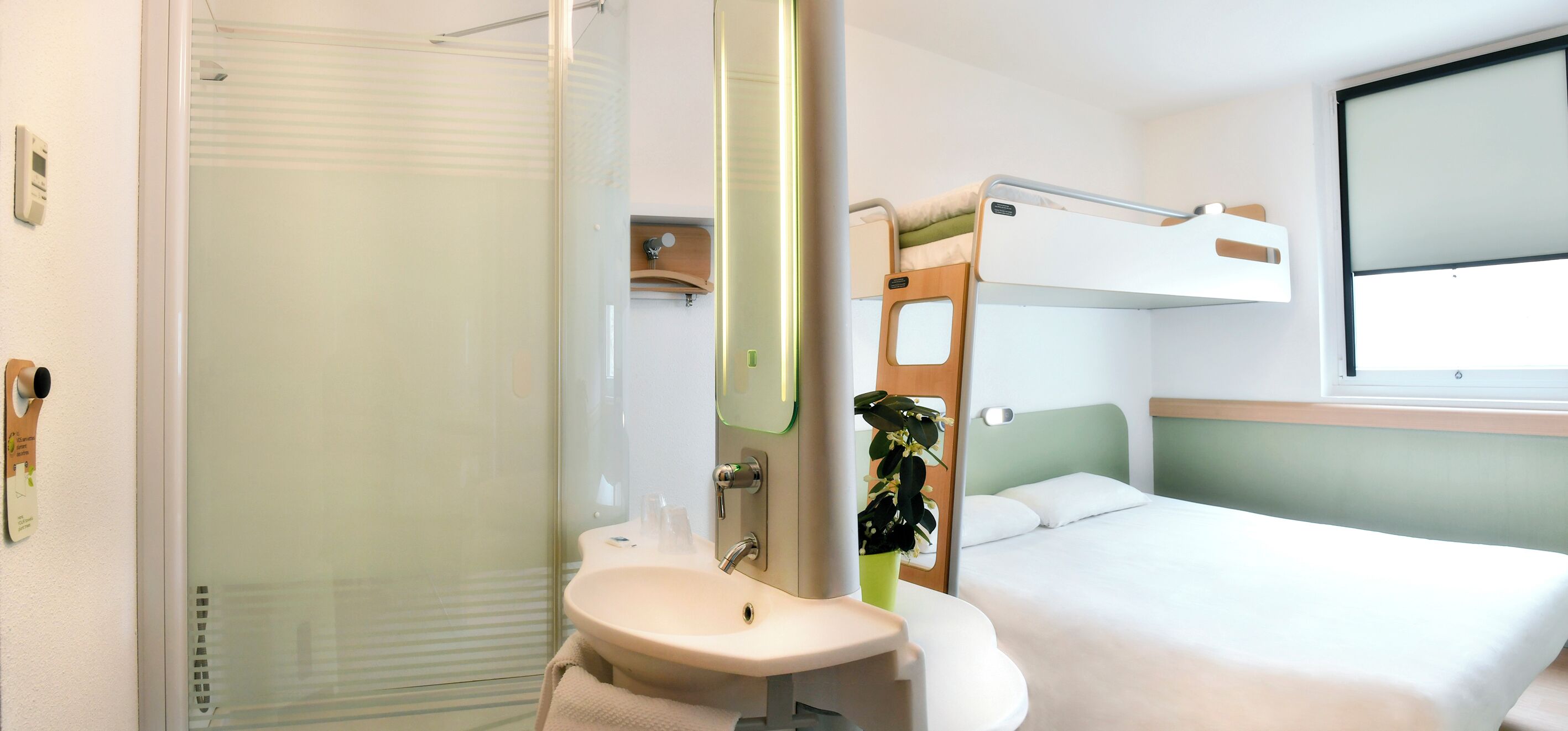 A hotel room with a shower, sink, and bunk beds.
