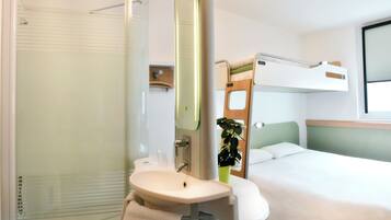 Hotelkamer met douche, wastafel en stapelbedden.