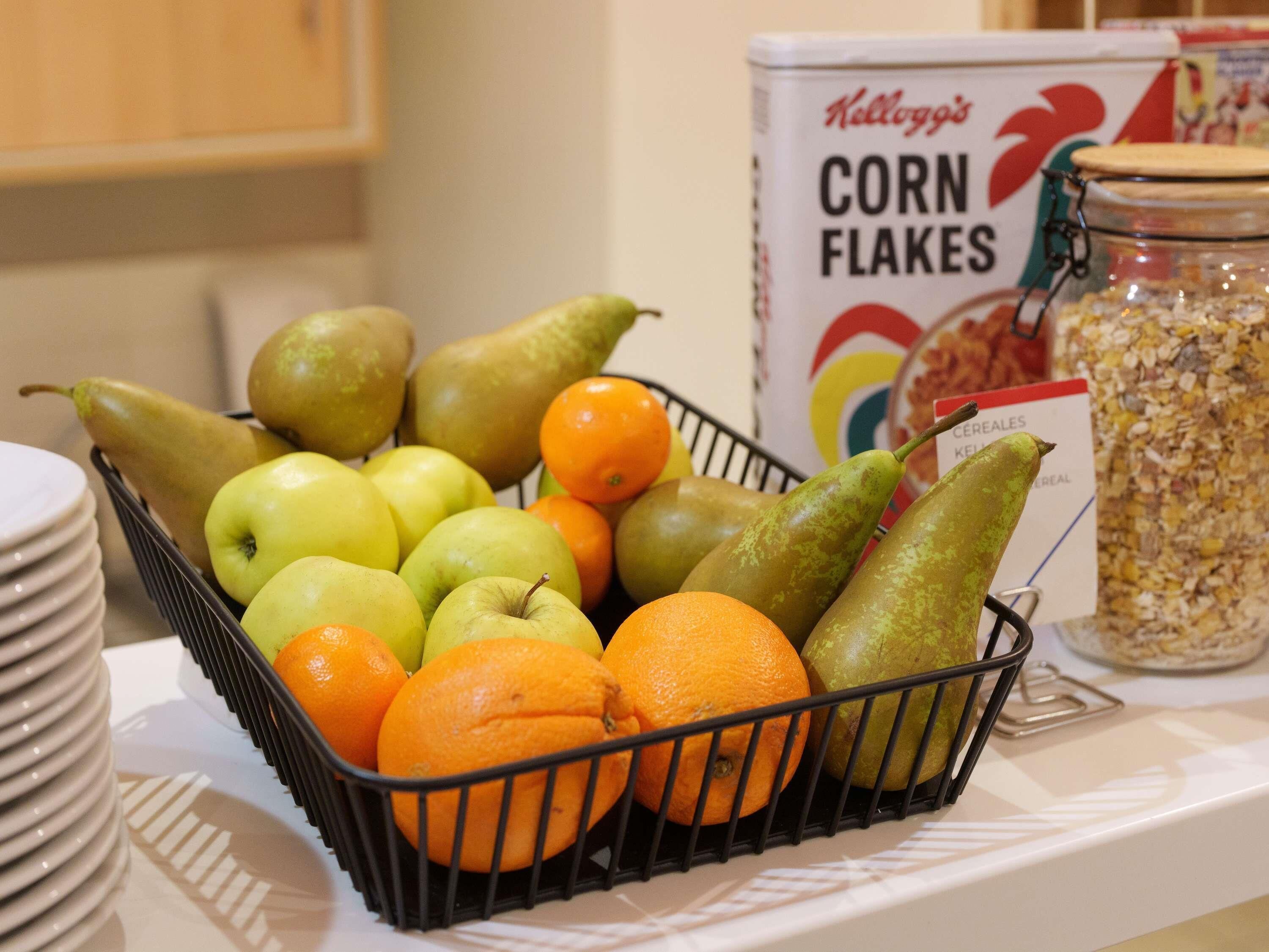 A fruit basket with pears, apples, and oranges on a table.