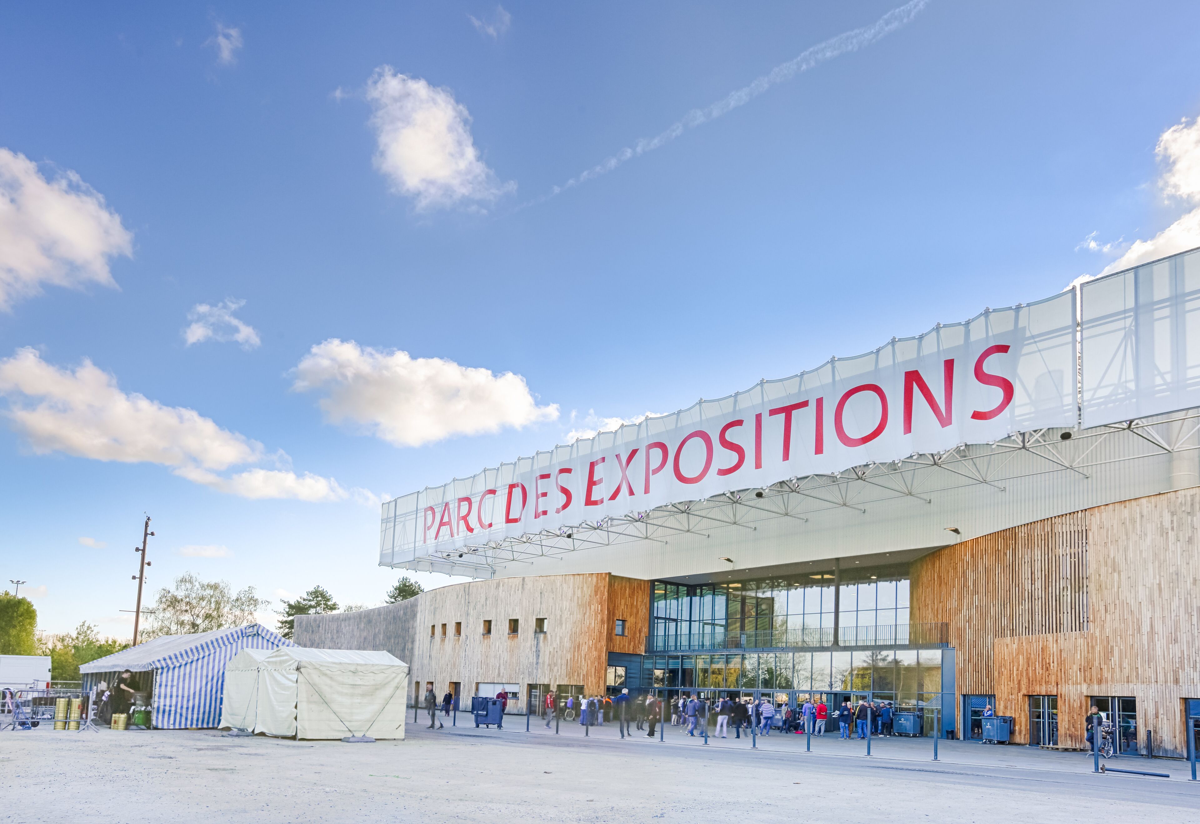 Un edificio grande con un letrero que dice "PARC DES EXPOSITIONS" y un área al aire libre cubierta con carpas.