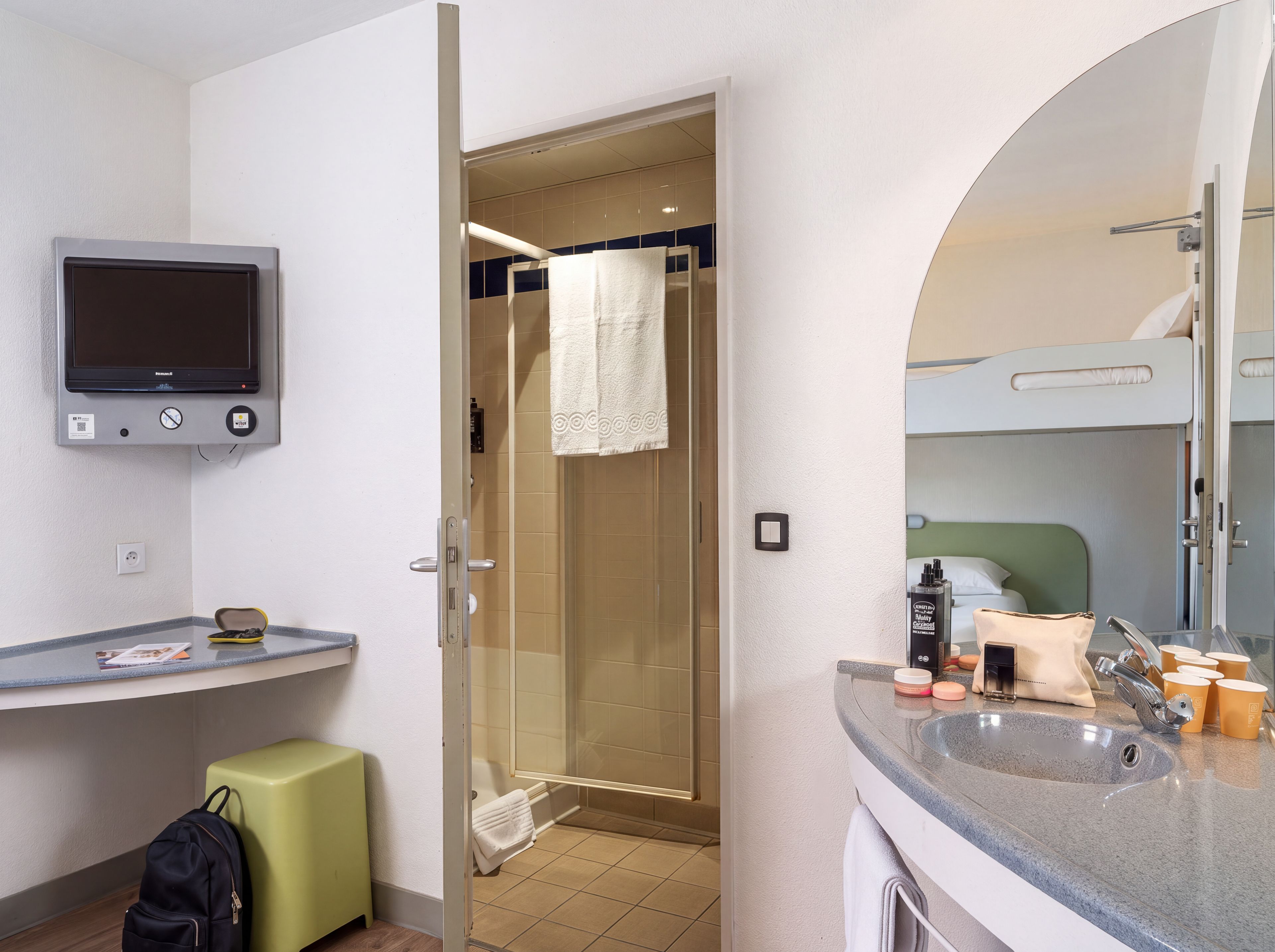 A modern bathroom with a shower, a sink, a mirror, and a television mounted on the wall.