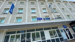 A hotel facade with multiple windows, a prominent 'ibis budget' sign, and a 'CANAL+' sign indicating a nearby location. - ibis budget Caen Centre Gare (Caen)