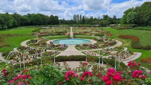 A landscaped garden with a central pool, surrounded by walking paths and flower beds. - ibis budget Caen Centre Gare (Caen)