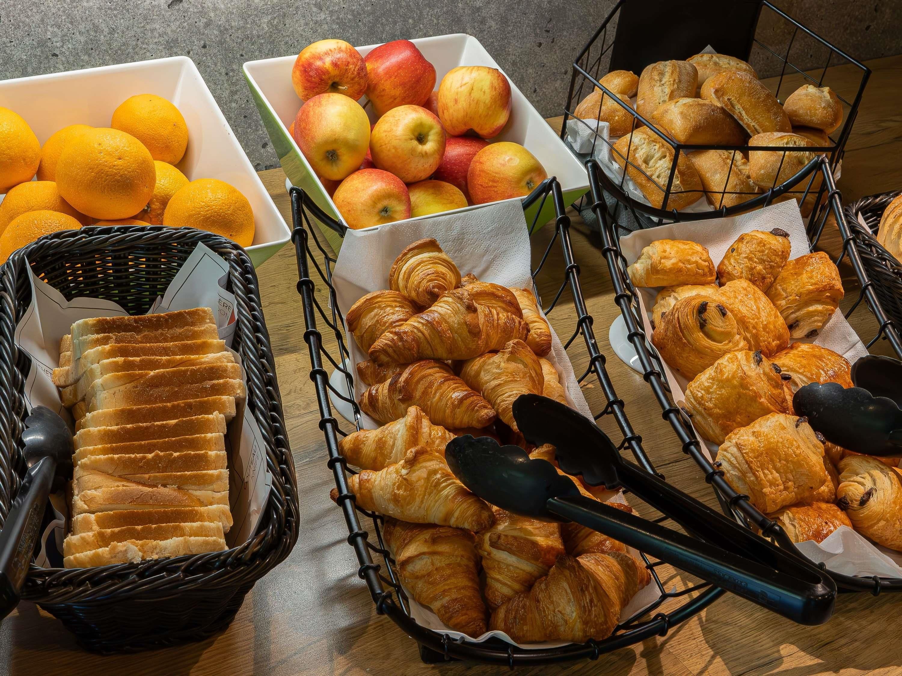 A variety of food items including bread, apples, and oranges arranged on a table.