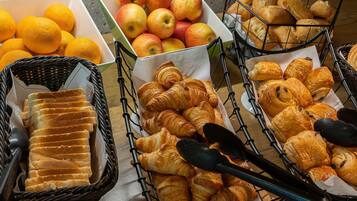 A variety of food items including bread, apples, and oranges arranged on a table.
