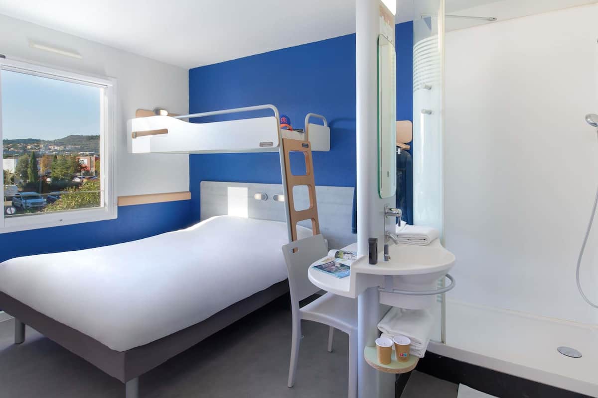 A bunk bed with a ladder, a desk, and a bathroom with a shower.