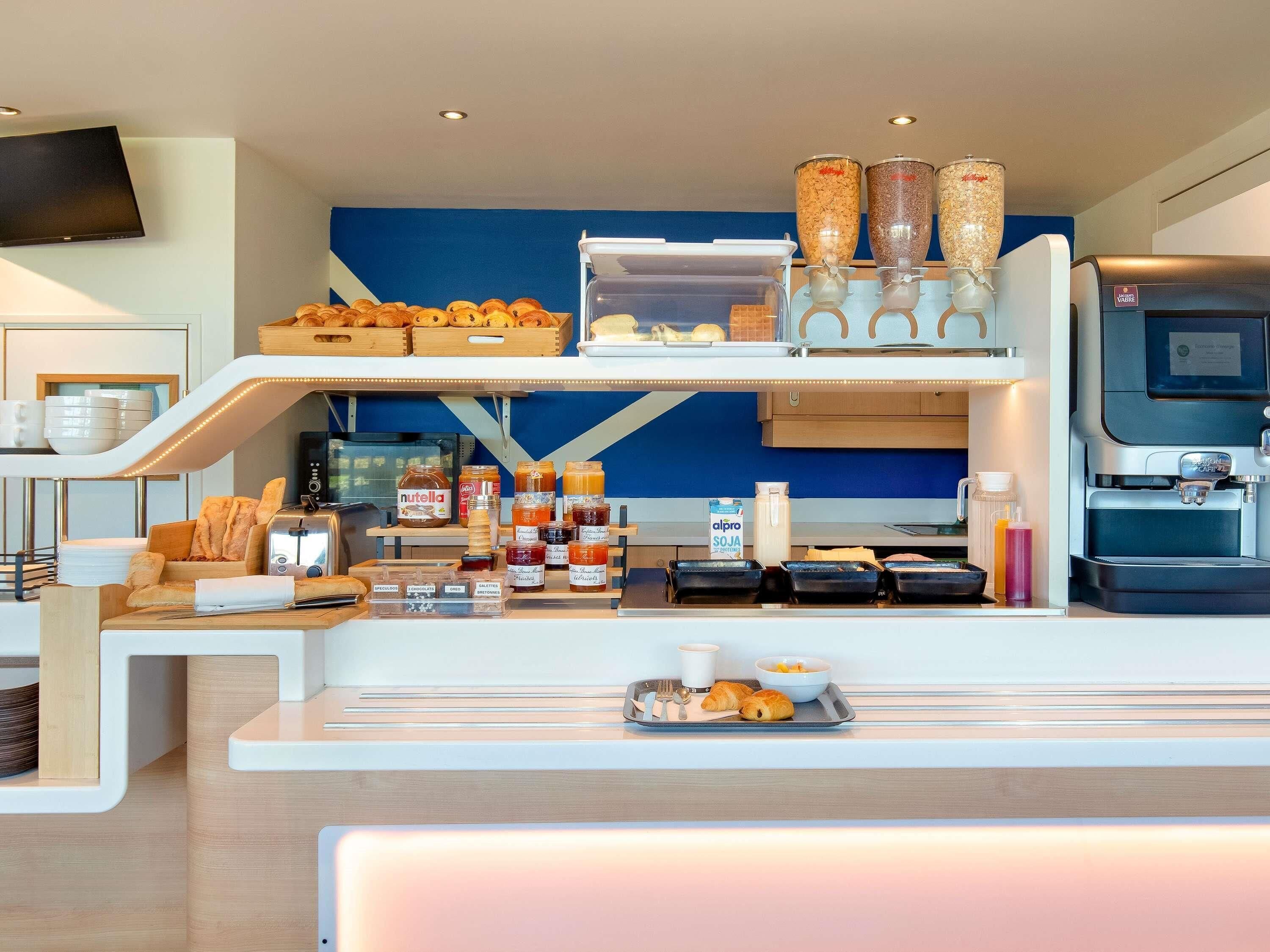 A breakfast bar with pastries, condiments, and a coffee machine.