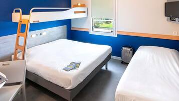 A hotel room with a bunk bed, a desk, a chair, a suitcase, a window with a view, and a TV mounted on the wall.