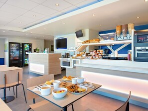 A modern reception area with a counter, a TV, and a coffee machine. - ibis budget Saint Maximin la Sainte Baume (Saint-Maximin-la-Sainte-Baume)