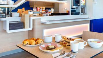 A breakfast buffet with pastries, coffee, and fruit bowls.