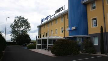 Un hotel llamado 'This Budget Hotel', con un diseño moderno, que cuenta con una zona de estar cubierta al aire libre y un estacionamiento.