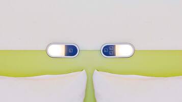 Casa de banho com lavatório branco, duas espelhas iluminadas e parede verde.