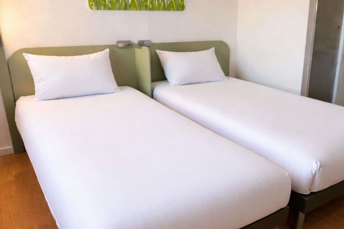 A twin room with two single beds, each with white linens and a green headboard.
