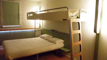A bunk bed room with a window, a bedside table, and a lamp.
