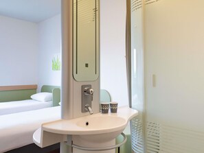 Una habitación de hotel con una cama, un lavamanos y un espejo.