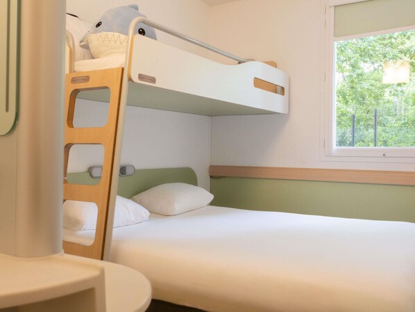 A bunk bed with a ladder, a bedside table, and a window with a view of trees.